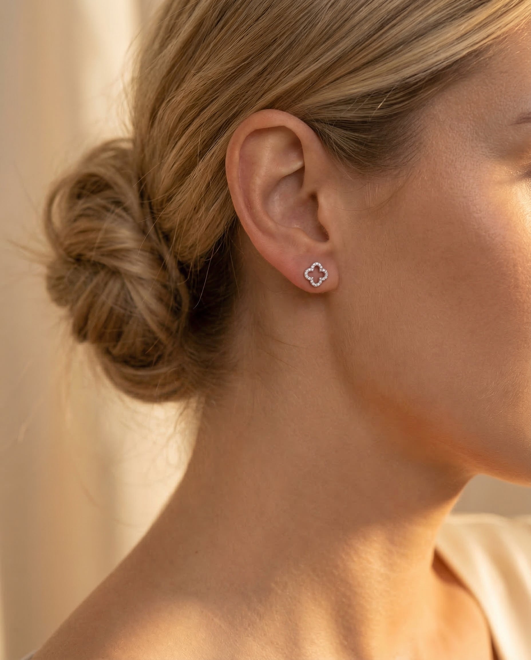 Boucles Trèfle — Chignon lâche, lumière golden hour, puce trèfle délicate
